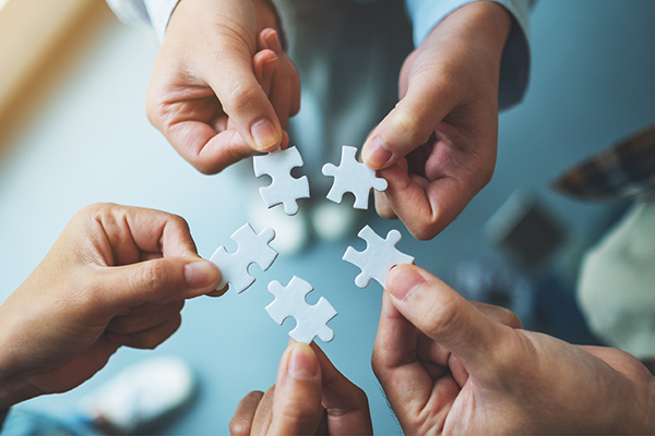 A group photo of hands holding onto a piece of puzzle.